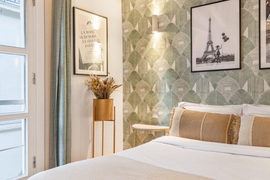 Chambre décorée avec lit, papier peint vert et cadres muraux